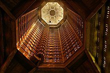 Vista de baixo ângulo da torre da lanterna banhada por uma luz laranja e sua escada helicoidal.