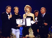 Da sinistra: Dorelli conduttore del Festival di Sanremo 1990, mentre premia Marco Masini insieme all'altra conduttrice Gabriella Carlucci.