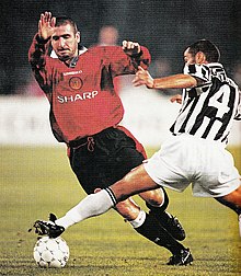 Cantona in azione con la maglia del Manchester Utd nel 1996, contrastato dallo juventino Montero in una sfida di Champions League.