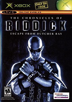 Um homem careca segurando duas facas e vestindo roupa preta, correntes e óculos. O homem está em frente de um fundo preto com o logo de "The Chronicles of Riddick: Escape from Butcher Bay" sobre sua cabeça. A classificação "M" da ESRB é exibida no canto esquerdo inferior e o loga da Vivendi Games no canto direito inferior.