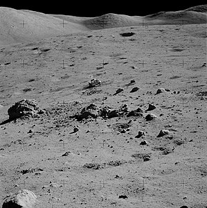 «Ровер» на Station 2 у кратера Нансен. Левее него — первый валун, с которым поработали астронавты. Правее «Ровера» видны его следы, ведущие вправо и вверх, к эскарпу