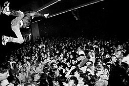 Один из фанатов прыгает в толпу со сцены во время концерта группы Nirvana (проходил в бальном зале Вашингтонского университета, 6 января 1990 года[110]), снимок был сделан фотографом Чарльзом Питерсоном, который проживал в Сиэтле и был свидетелем расцвета гранж-сцены[111]
