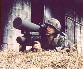 De schutter van de 187th Infantry Brigade mikt met een complex op zijn schouder op het doelwit van achter een hooiberg op het trainingspunt "battle in urban conditions"