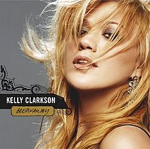 Một cô gái với mái tóc vàng bay trước gió, ở bên phải của cô có hai dòng chữ "Kelly Clarkson" và "Breakaway" được in trên một vector xoay.