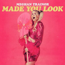 一位身穿粉紅裙子並拿著道具的金髮女子，上方則印著「Meghan Trainor Made You Look」的字樣