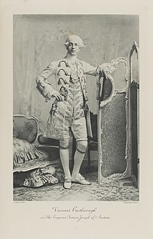Black-and-white photograph of a standing man richly dressed in an historical costume and a white wig